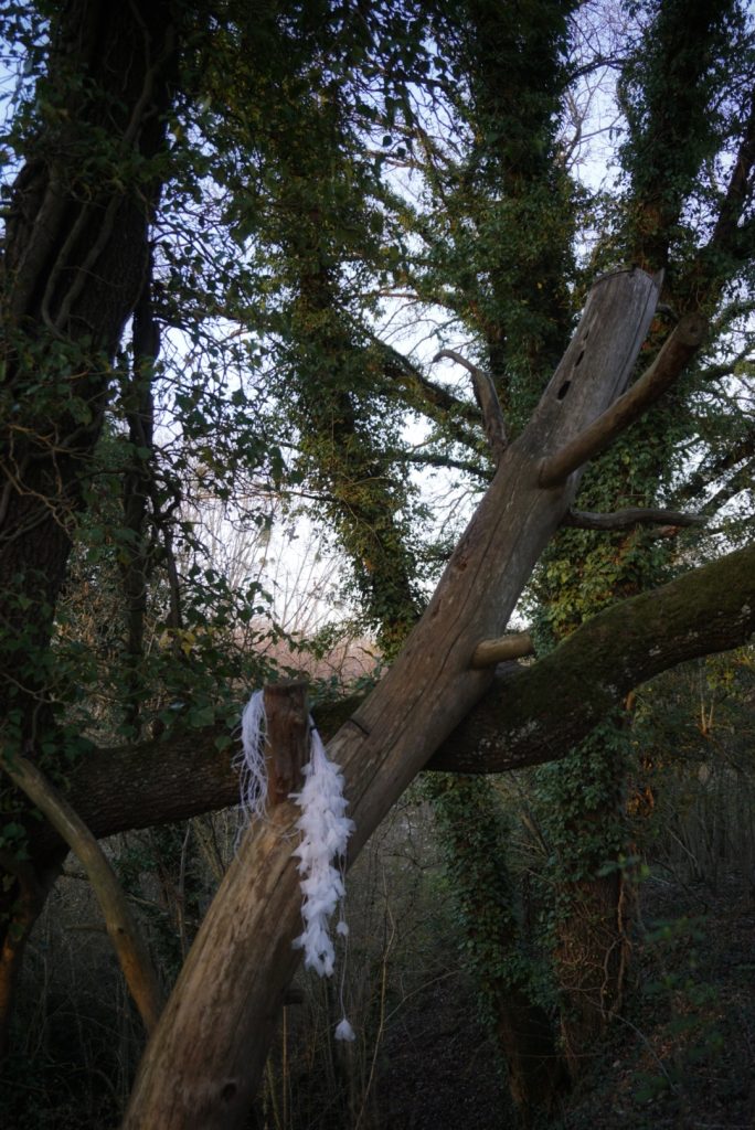 Sculpture en papier calque et ficelle blanche accrochée dans les arbres