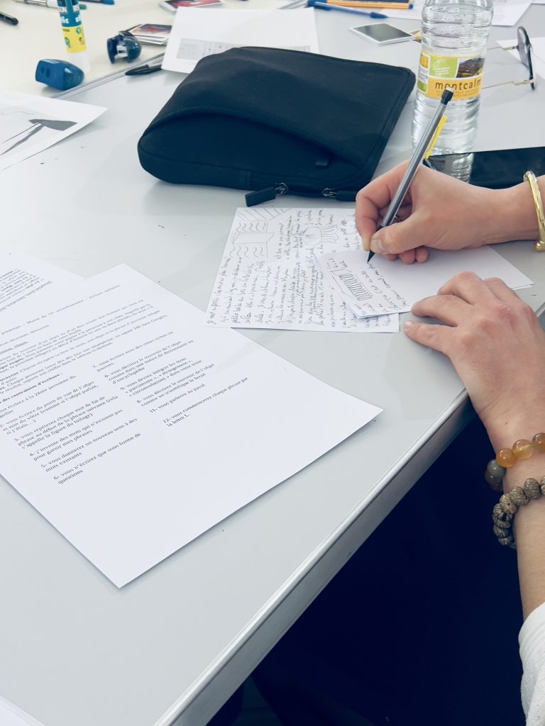 Photo d’une participante dont on voit seulement les mains et le stylo en train d’écrire sur un papier blanc