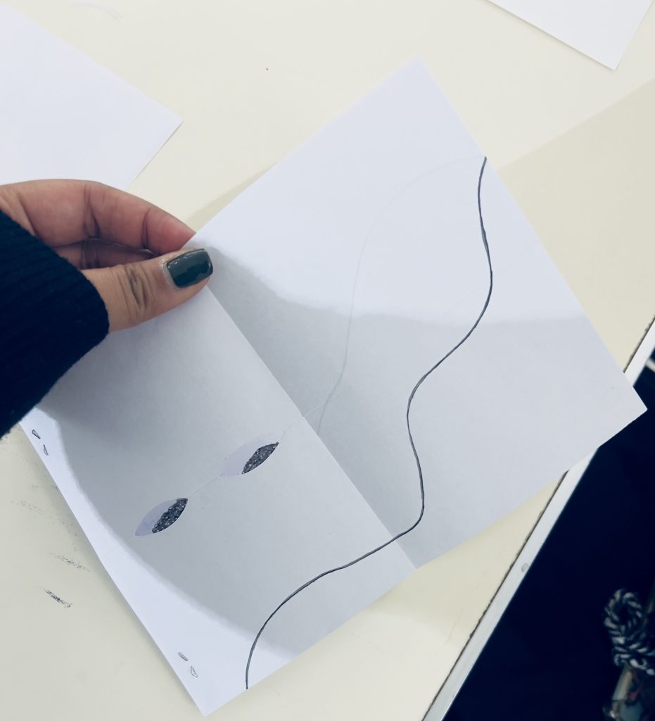 Photo, photographie d’une participante dont on voit seulement la main qui montre ce qu’elle a produit sur son papier blanc