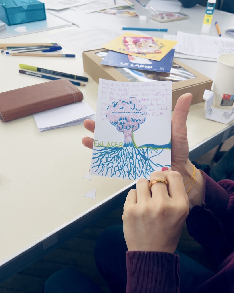 Photo, photographie d’une participante dont on voit seulement la main qui montre ce qu’elle a produit sur son papier blanc